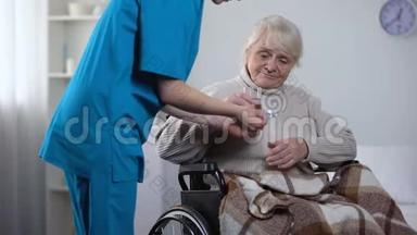 年轻护士给轮椅上的老太太送药，康复中心